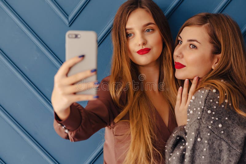 Two Attractive Stylish Young Girls With Phone On Simple Aqua Background ...