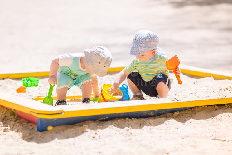 Two baby boys playing with sand