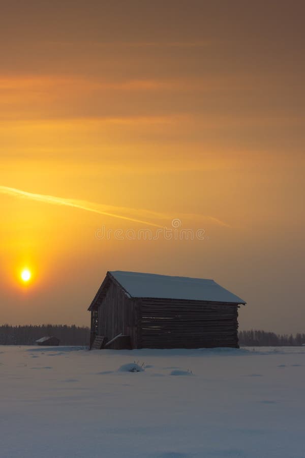 Two Barns In The Winter Sunrise. A beautiful but cold morning in the rural Finland. The sun rises and colors the overcast sky beautifully stock image Two Barns In The Winter Sunrise. A beautiful but cold morning in the rural Finland. The sun rises and colors the overcast sky beautifully stock image