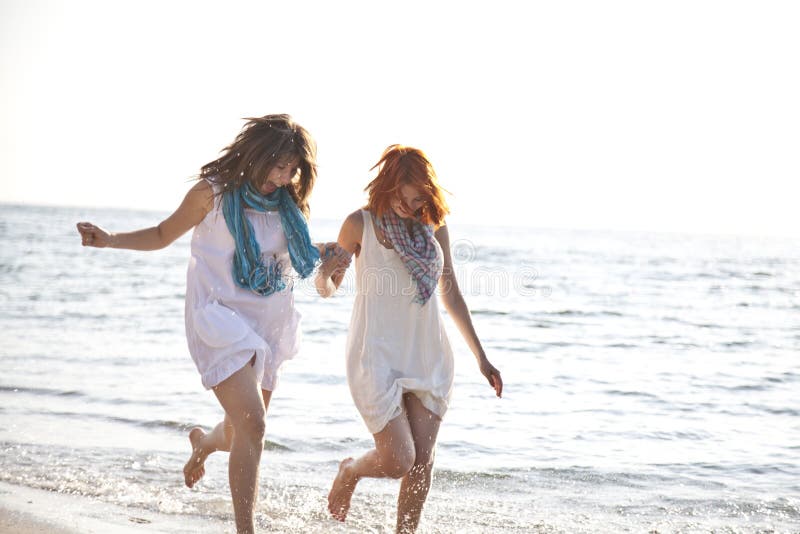 Two beautiful girls running on the beach.