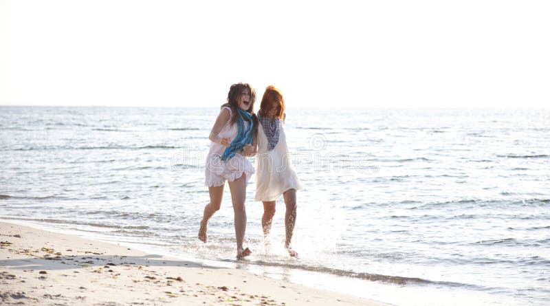 Two beautiful girls running on the beach.