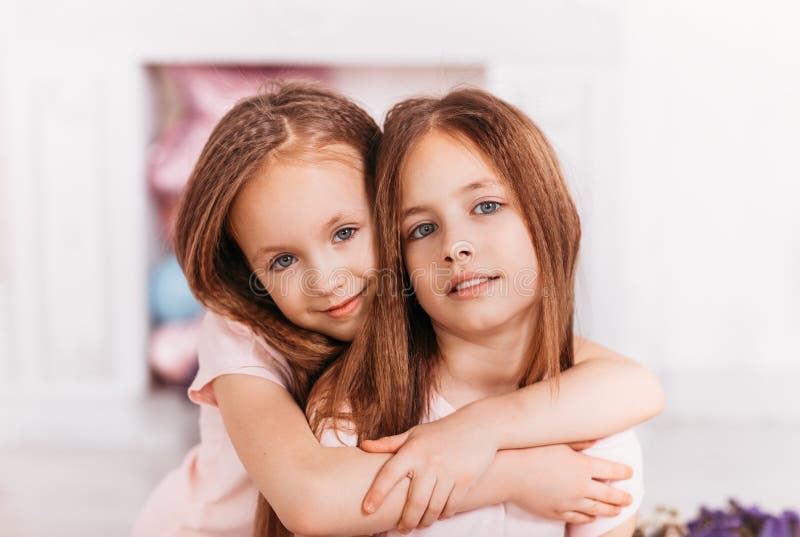 Two Beautiful Girls Sisters Hug Each Other In A Light Room Stock Image 