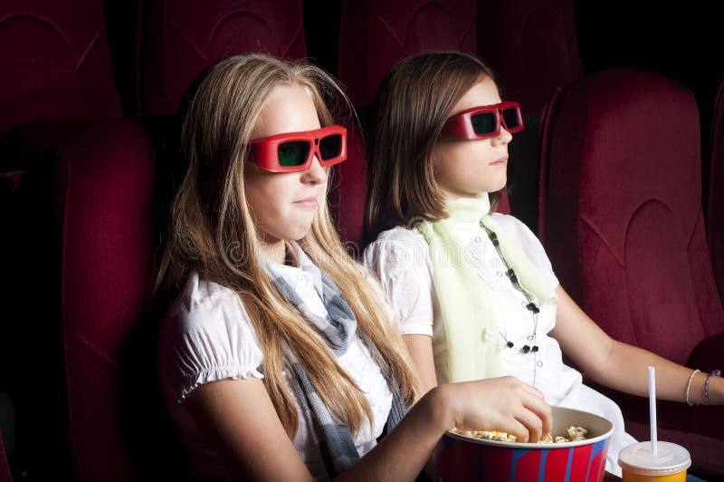 Two beautiful girls watching a movie at the cinema