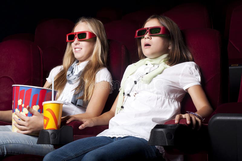 Two beautiful girls watching a movie at the cinema