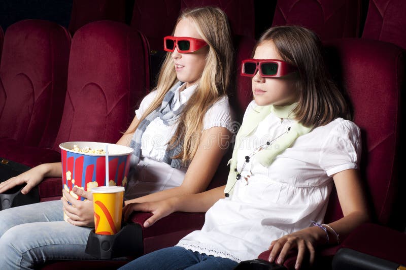 Two beautiful girls watching a movie at the cinema