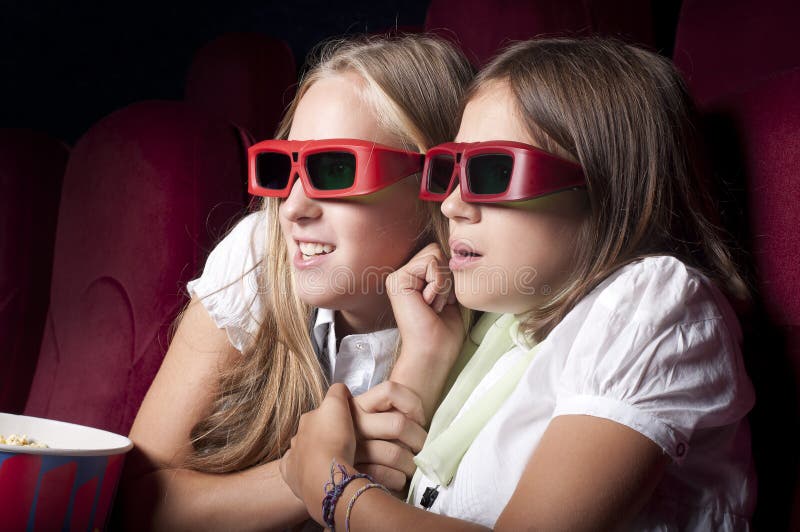 Two beautiful girls watching a movie at the cinema