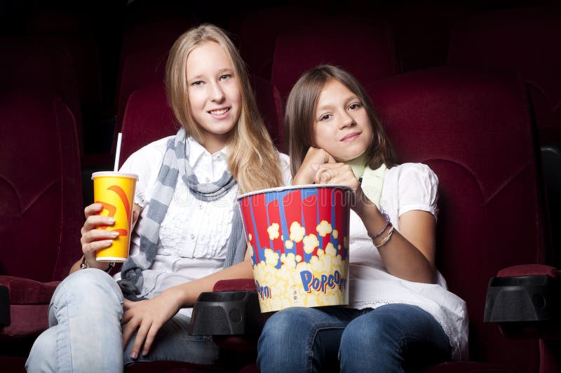 Two beautiful girls watching a movie at the cinema