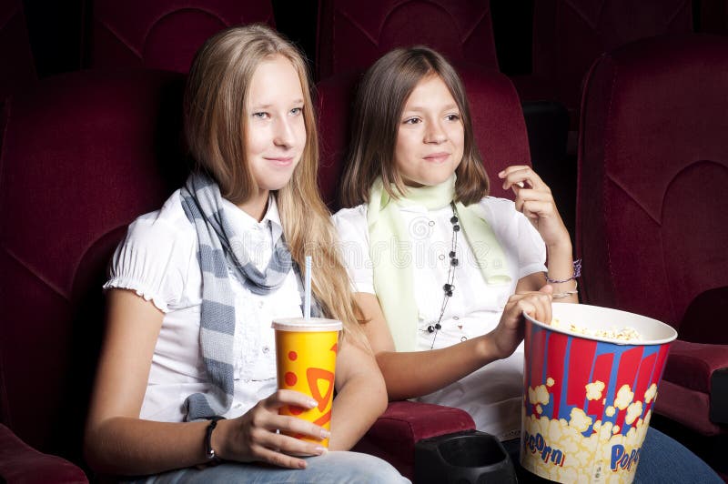 Two beautiful girls watching a movie at the cinema