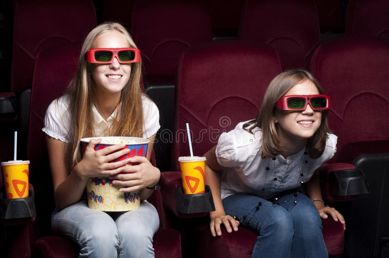 Two beautiful girls watching a movie at the cinema