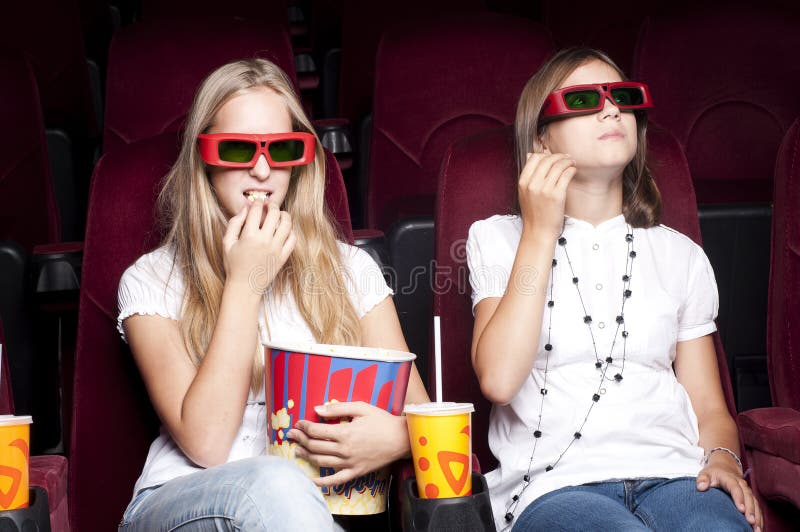 Two beautiful girls watching a movie at the cinema