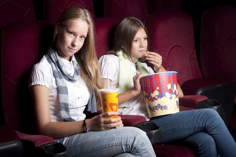 Two beautiful girls watching a movie at the cinema