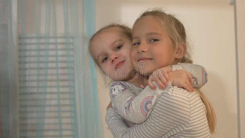 Two little girls smile and hug at home