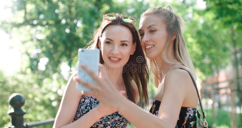 Two beautiful teenage girls using phone in a city park. Two beautiful teenage girls using phone in a city park.