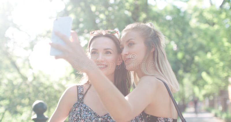 Two beautiful teenage girls using phone in a city park. Two beautiful teenage girls using phone in a city park.