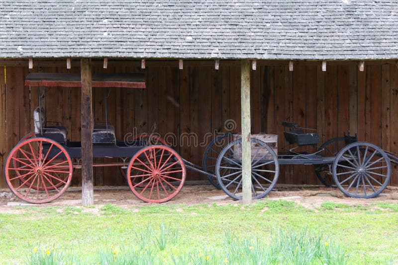 Two beautiful vintage horse cart trap vehicle next to a rustic barn stable building. Stable rustic style stock images, royalty-free photos and pictures