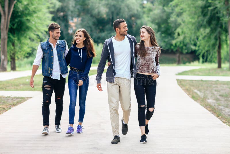 Two beautiful young lovers couple walking in summer park