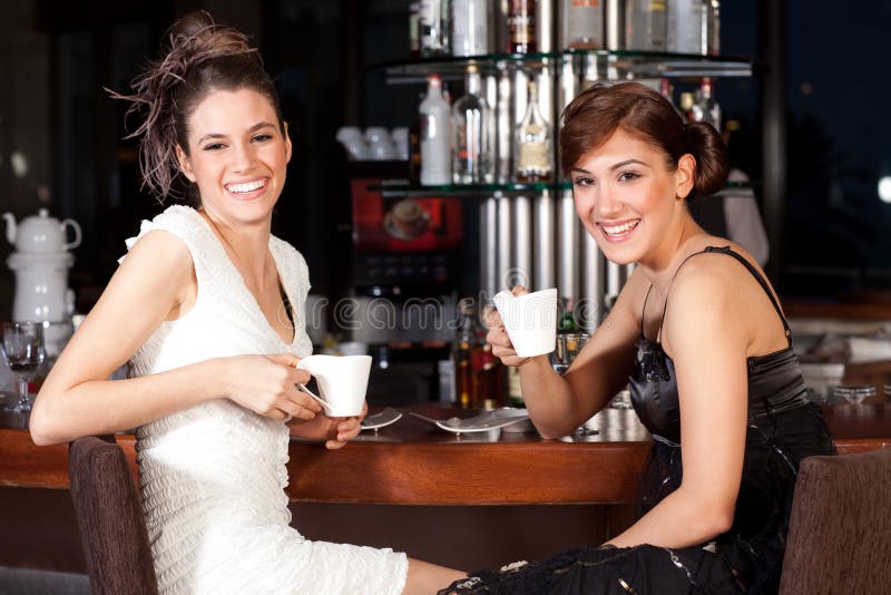 Two beautiful young women drinking coffee at bar