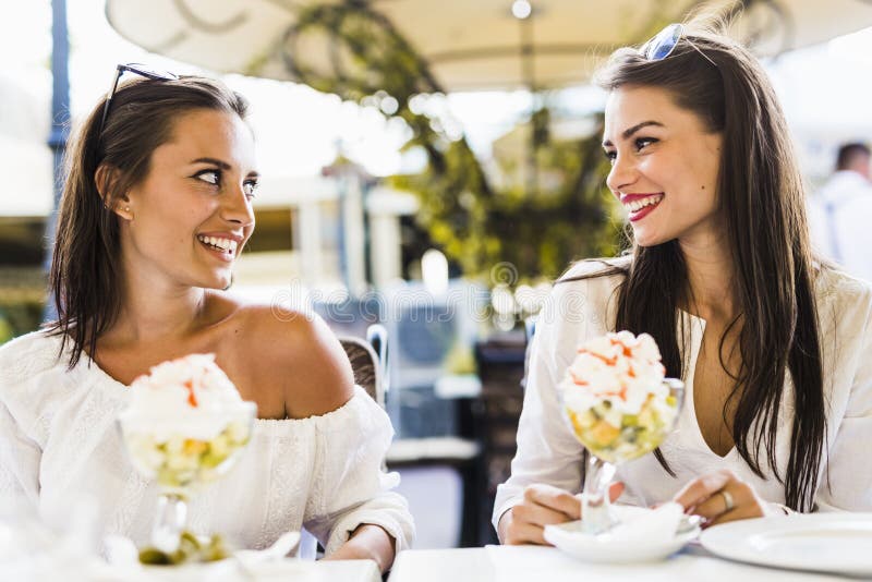 Two beautiful young women smiling and having a fruit salad in a stock image