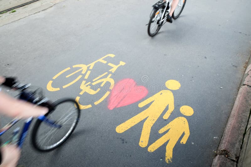 Two bikes passing by the pedestrian/bicycle sign