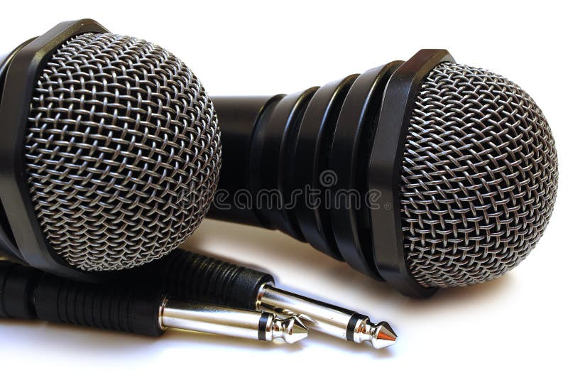 Two black wired karaoke microphones with gray metal grill on isolated background. Two black wired karaoke microphones with gray metal grill on isolated background.