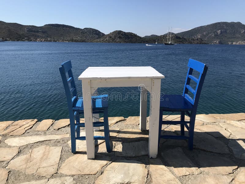 Blanco de madera mesa dos azul vacío sillas más cercano el arruinar en soleado.