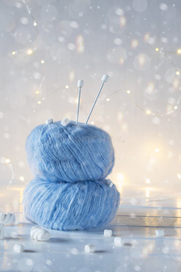 Two blue fluffy ball yarn and knitting needles. Christmas background.