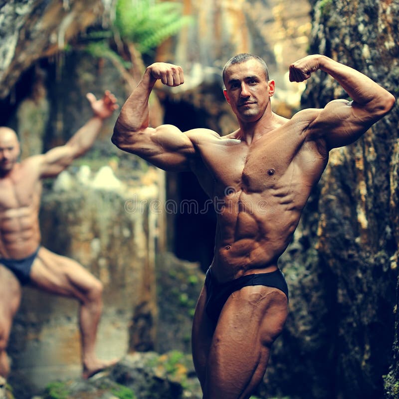 Two bodybuilders posing in a cave royalty free stock photo