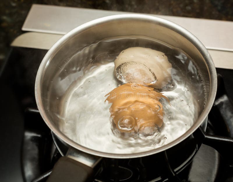 Two boiling eggs in stainless saucepan