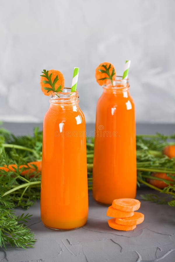 Two Bottles with Fresh Carrot Juice and Carrot with Green Stock Photo