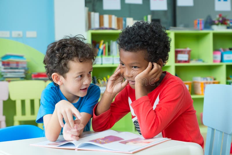 Two boy kid sit on table and reading tale book in preschool library,Kindergarten school education concept
