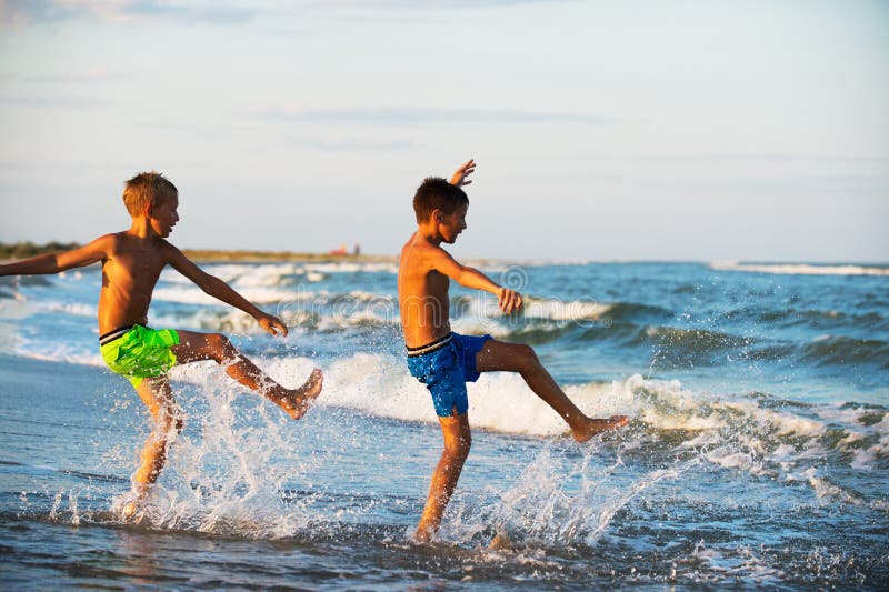 Two Boys Adolescence Playing In The Sea Water Splashing Feet Water