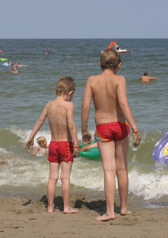 Two boys at the beach, staring at the sea