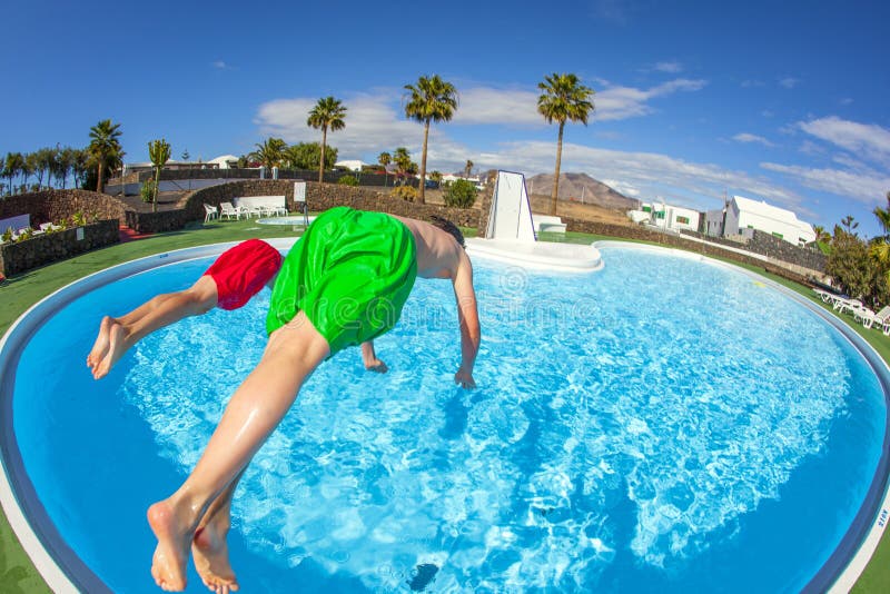 Two boys jumping in the blue pool