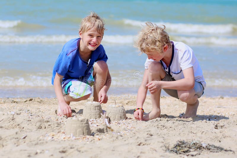 Two boys playing with sand on the beach stock images Two boys playing with sand on the beach stock images