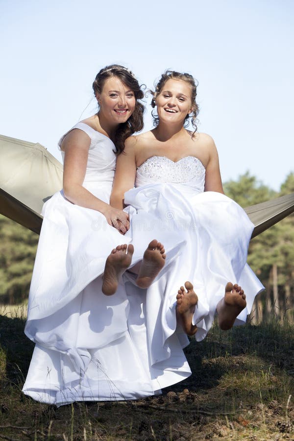 Two brides in hammock against blue sky with forest background stock photos Two brides in hammock against blue sky with forest background stock photos
