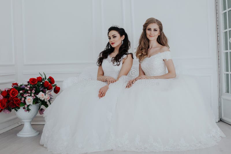 Two Brides in Wedding Dresses Sit on a ...