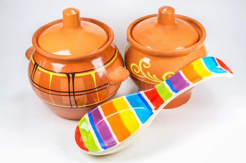 Two brown clay pots with colored ceramic spoon on white background