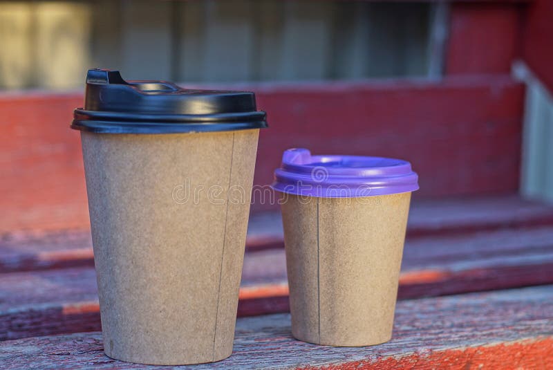 Two brown paper cups with coffee closed with plastic lids stock photography