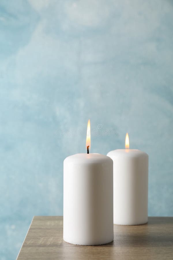 Two burning candles on grey table against background, space for text royalty free stock photos