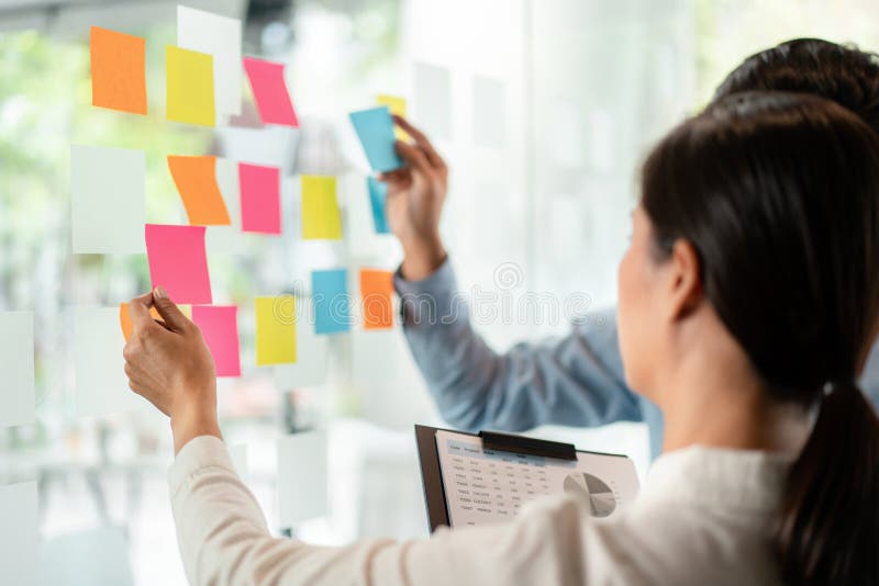 Two business executive team holding and taking notes keyword on board wall to brainstorm about a new business project for planning stock image
