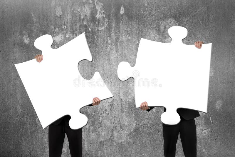 Two business people assembling white jigsaw puzzles with concrete wall royalty free stock photo