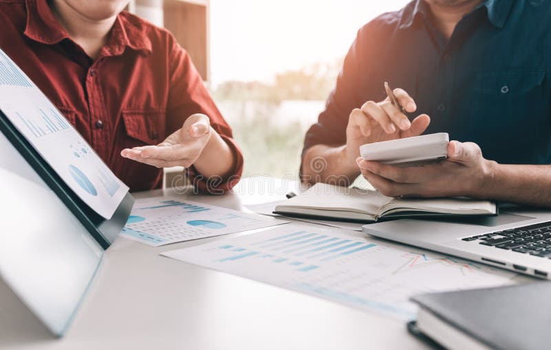 Two business people are calculating earnings financial costs of the company on desk at the office room