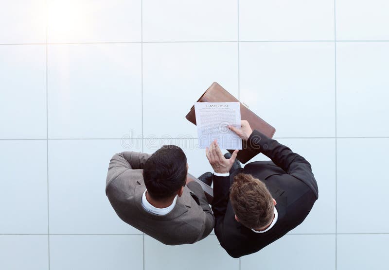 Two businessman signing an agreement. One hand holds the document and the other signs. royalty free stock image