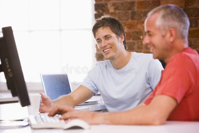 Two businessmen in office typing on computer