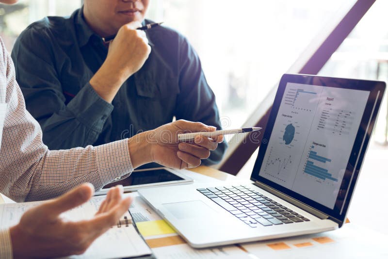 Two businessmen are together analyzing the financial data graph and pointing to the laptop computer screen stock photos