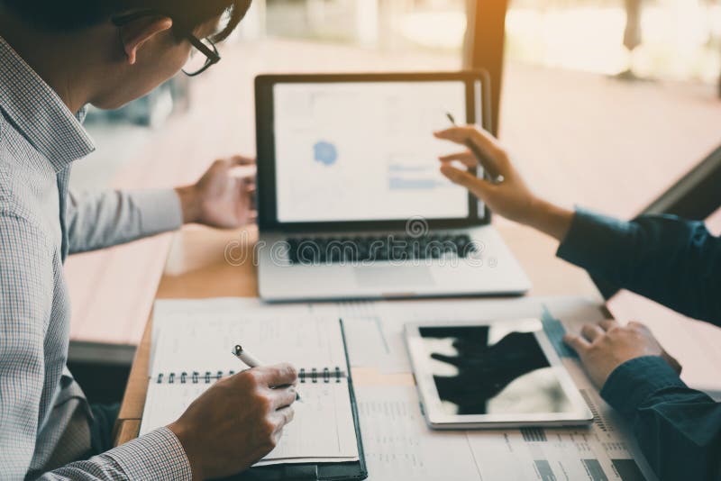 Two businessmen are together analyzing the financial data graph and pointing to the laptop computer screen royalty free stock photography