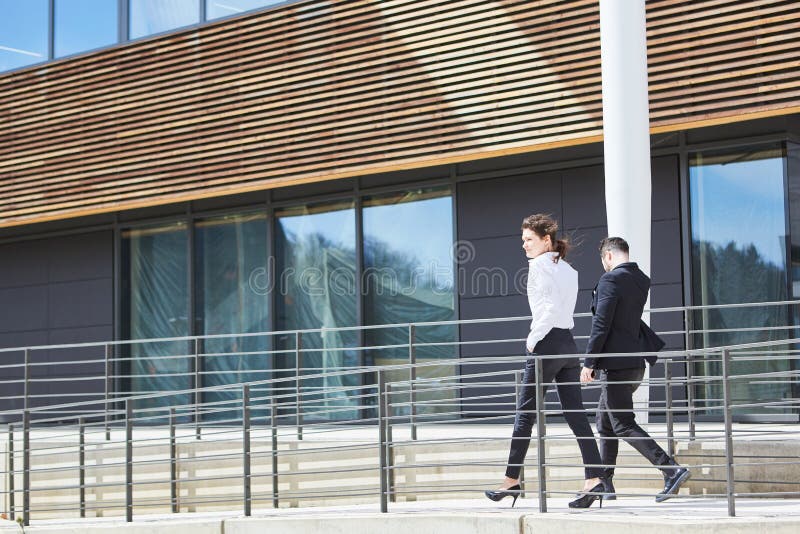 Two business people in a hurry in front of the office building royalty free stock images Two business people in a hurry in front of the office building royalty free stock images