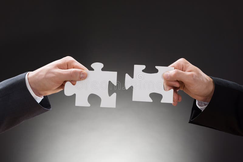 Two businesspeople holding jigsaw puzzle pieces royalty free stock photo Two businesspeople holding jigsaw puzzle pieces royalty free stock photo