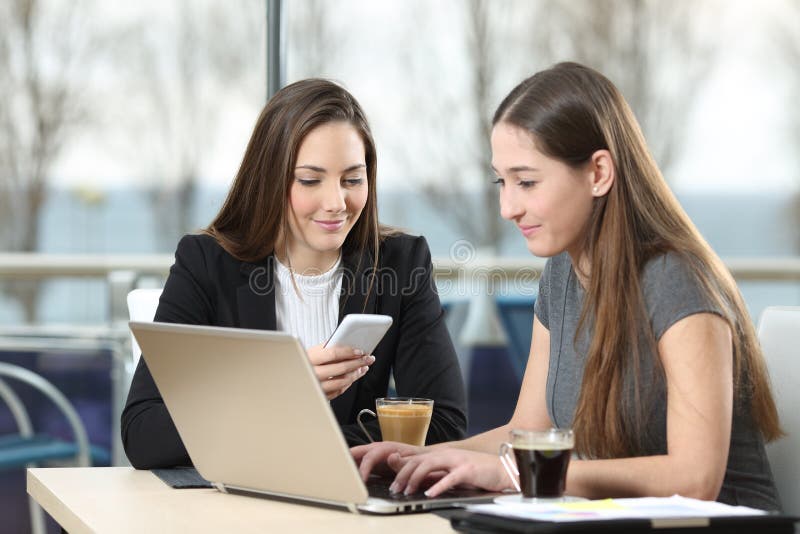 Two businesswomen working on line in a coffee shop stock images Two businesswomen working on line in a coffee shop stock images