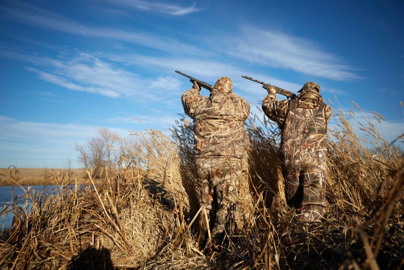 Two duck hunters shooting into sky with rifles